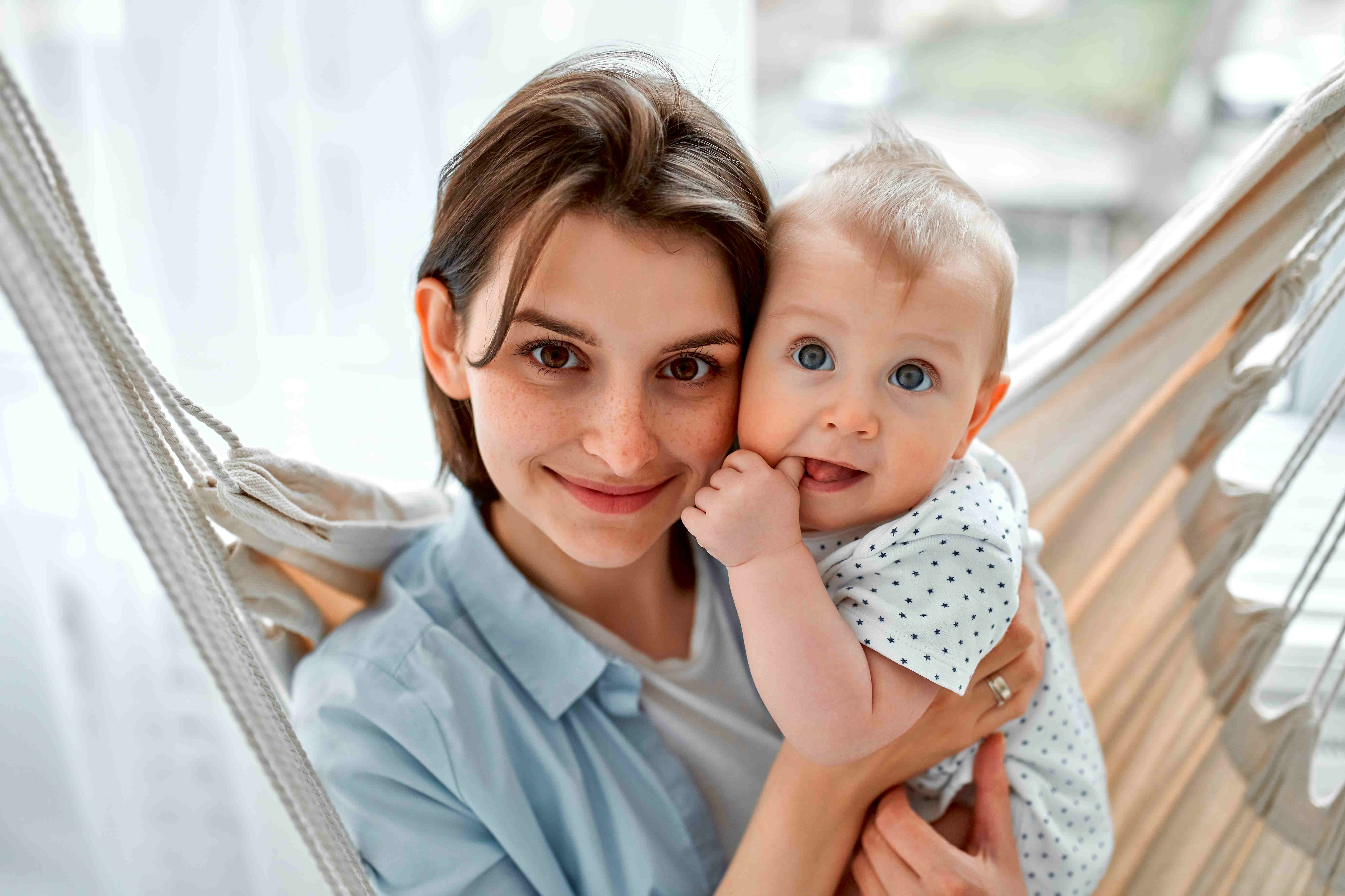 Smiling mother holding her baby cheek-to-cheek in a hammock