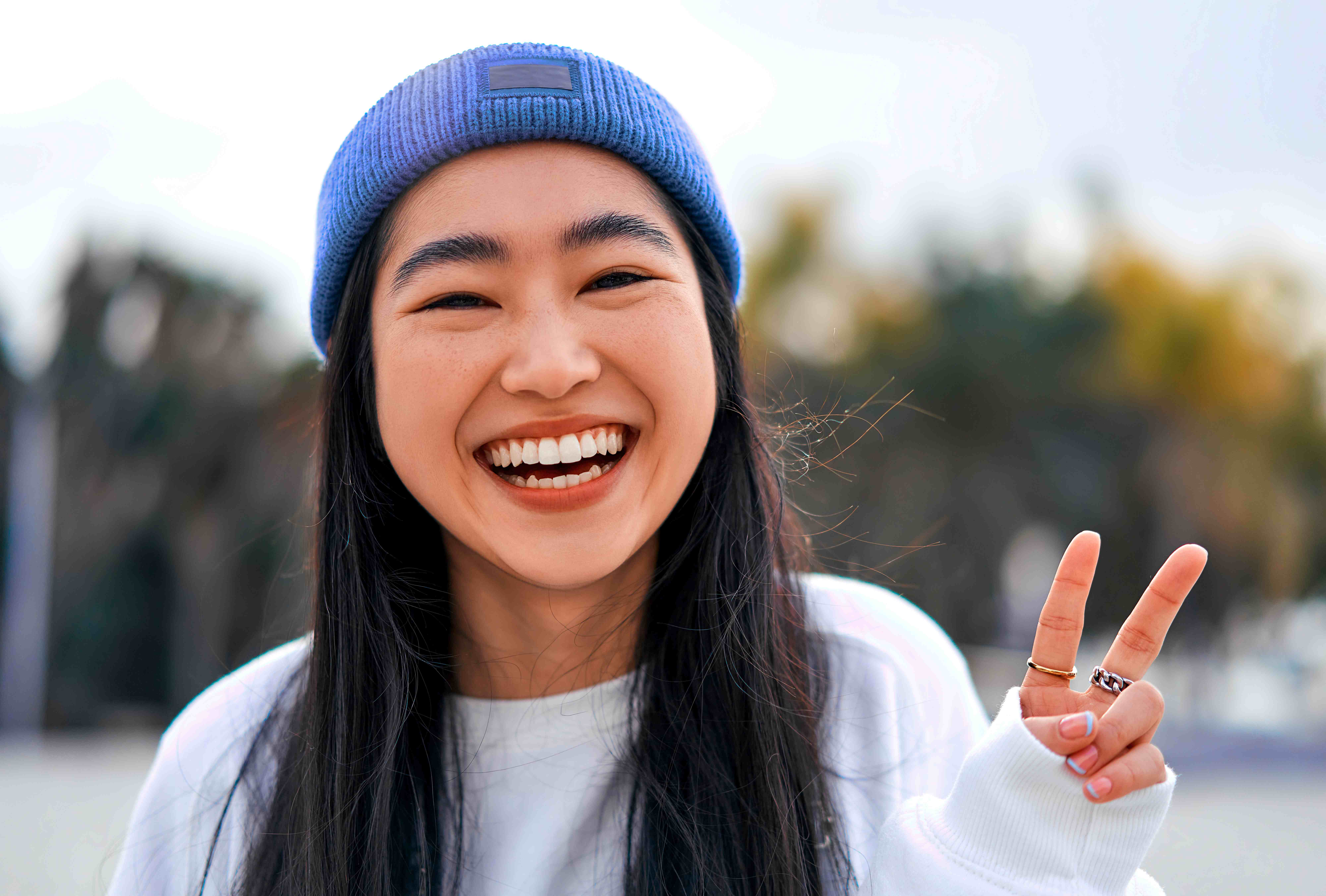 Smiling young woman in a beanie making a peace sign